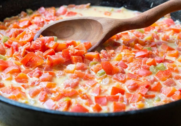 A skillet filled with sauce for chicken alfredo casserole