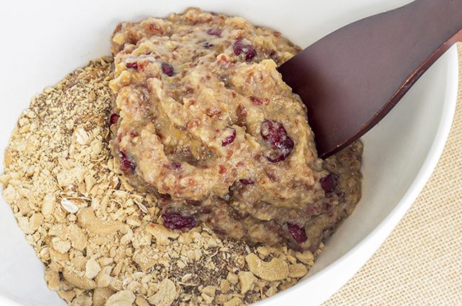 An image of mixing together the wet and dry ingredients for apple pie healthy oatmeal bars in a large white bowl with brown spoon