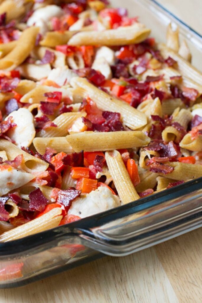 Baking dish filled with chicken and pasta casserole with bacon