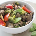 Up close picture of a white bowl of beef stir fry with vegetables