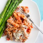 chicken parmesan casserole on a white plate with asparagus