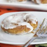 pumpkin donut on a white plate with a fork