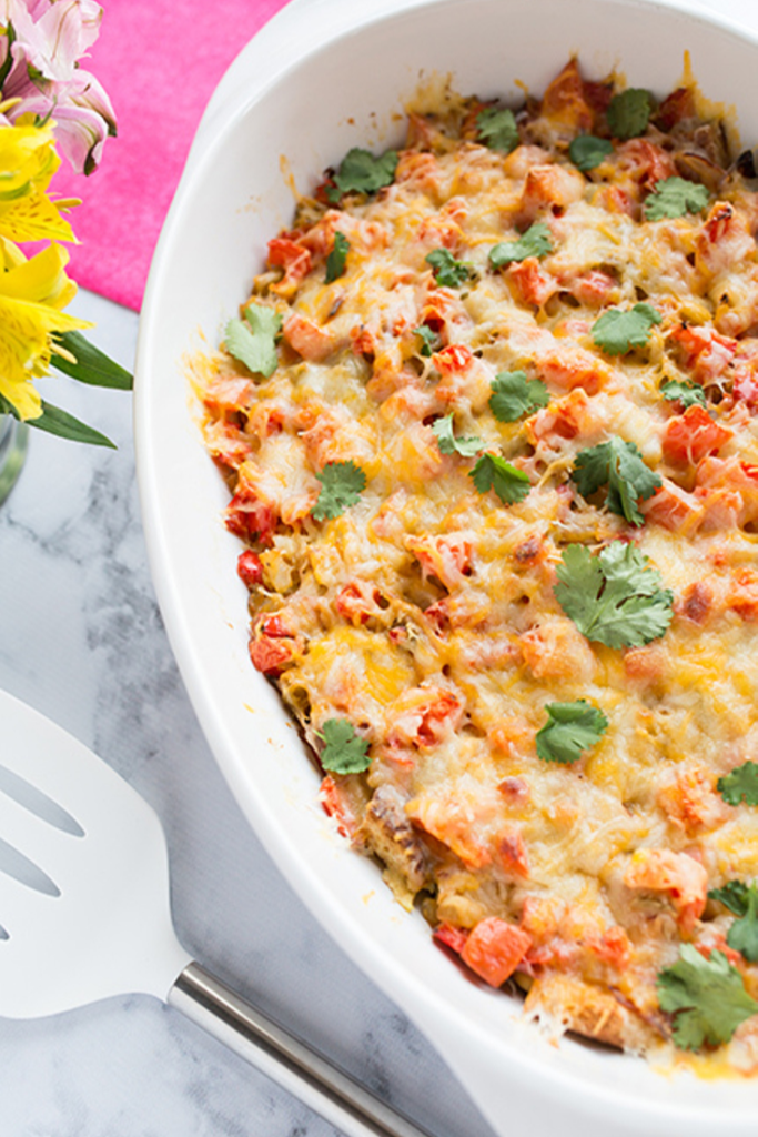 Overhead picture of breakfast casserole in white dish on marble counter with flowers in background