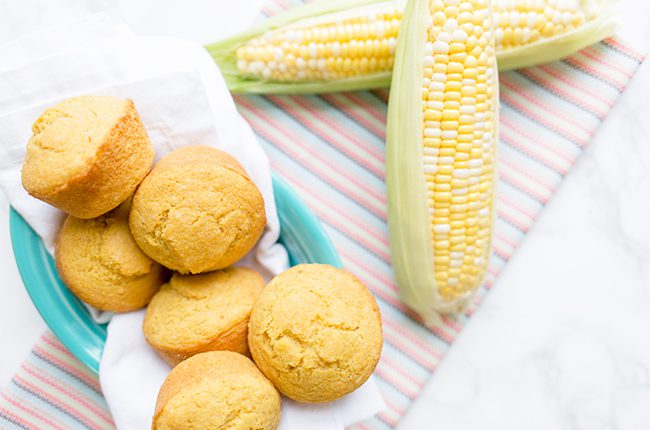 Overhead picture of muffins on blue plate with ears of corn in background