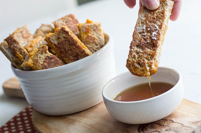 dipping pumpkin french toast into a white bowl