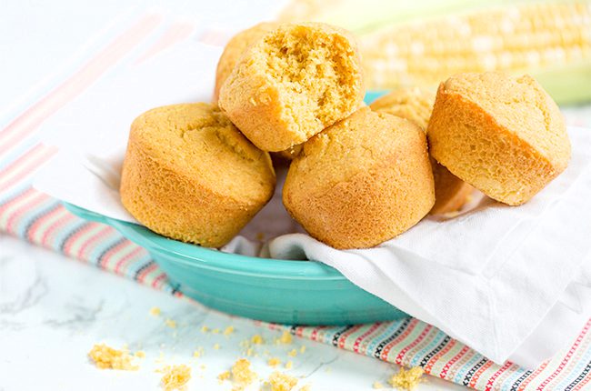 Side picture of cornbread muffins in blue plate on colorful cloth napkin