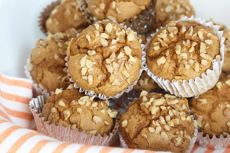 Prepared pumpkin spice muffins stacked together on an orange cloth