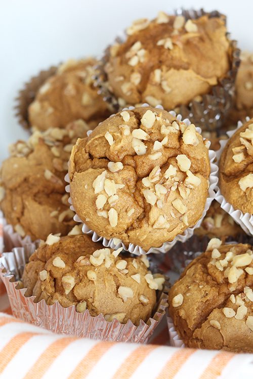 A large stack of pumpkin spice muffins on an orange and white striped napkin