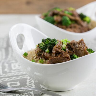 Square picture of Mongolian beef in large white bowl with brown rice