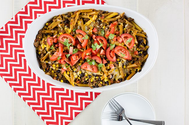Overhead picture of a tex mex casserole on a red and white chevron cloth