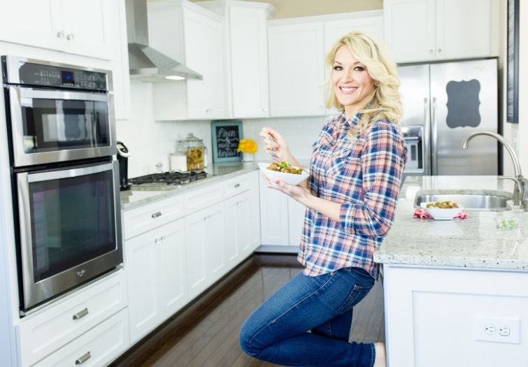 Brooke Farmer leaning against counter with a bowl of chicken meatballs and rice