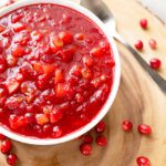Overhead picture of white bowl filled with cranberry apple chutney sitting on a wooden surface