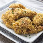 Crispy fried chicken recipe on a white plate that is sitting on top of a blue plate