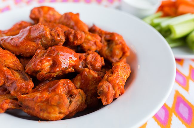 Up close picture of a large white bowl filled with buffalo chicken wings