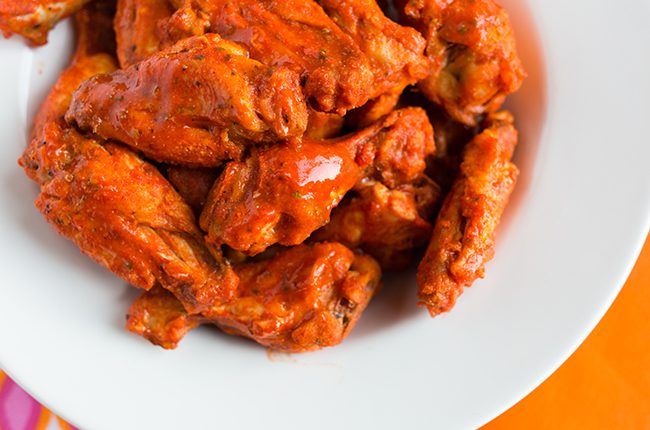 Up close overhead picture of a white bowl filled with buffalo wings