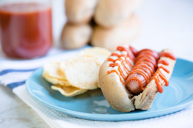 homemade ketchup on hot dog with bun on a plate