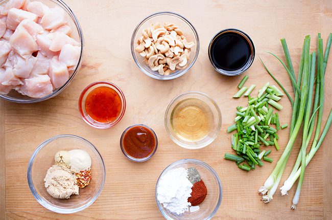 Ingredients for slow cooker cashew chicken recipe in bowls on wooden table