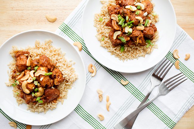 Two plates of cashew chicken recipe on a green and white cloth napkin