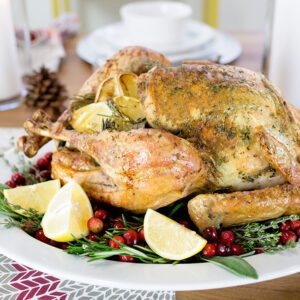 A roasted thanksgiving turkey sitting on a large white platter ready to serve