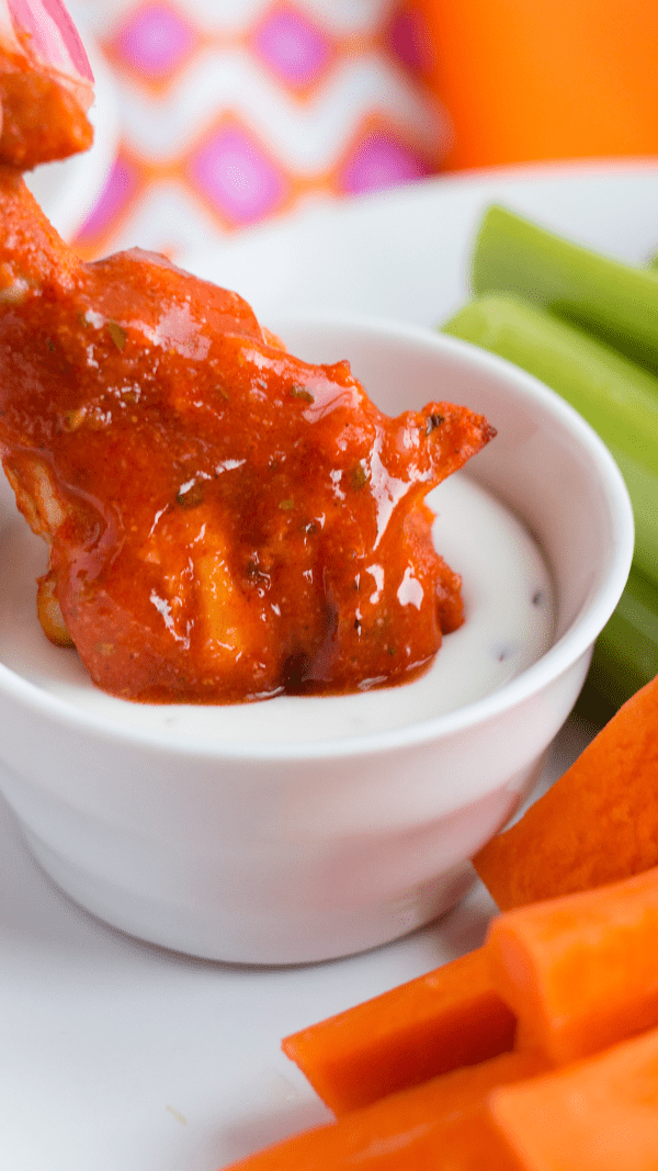 Dipping baked wings into sauce