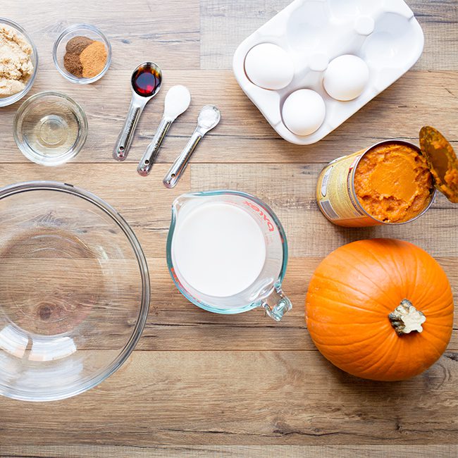 Ingredients for pumpkin pie sitting on a wooden counter
