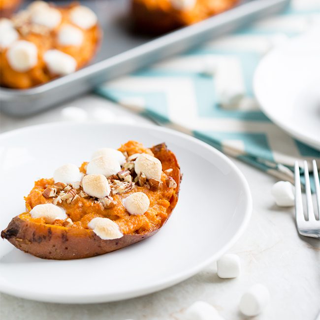 Twice baked sweet potato sitting on a white plate with a blue and white cloth on the table in the background