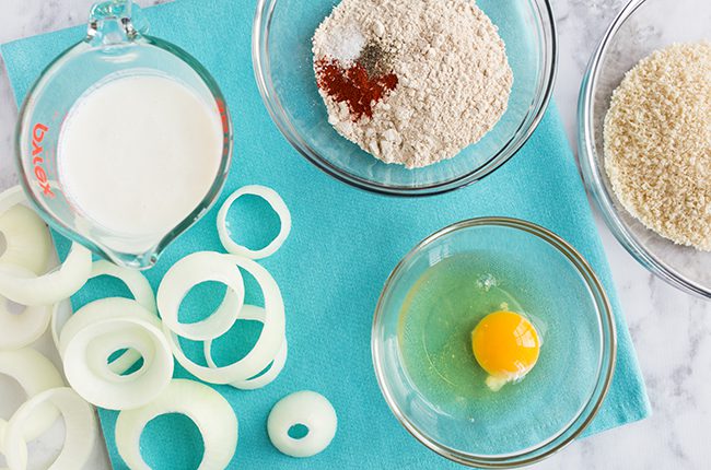 Ingredients for onion rings laying on a blue cutting board