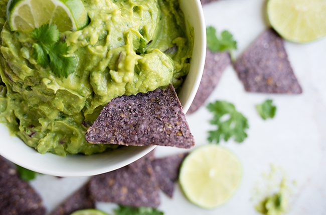 Picture of a bowl of an authentic guacamole recipe with blue corn tortilla chips