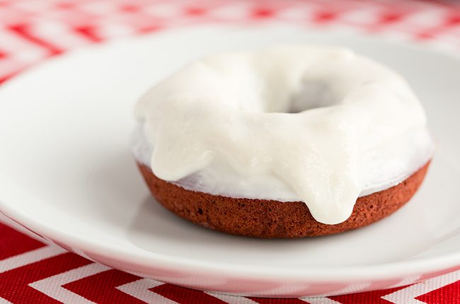 Red Velvet Donut sitting on a white plate covered in glaze