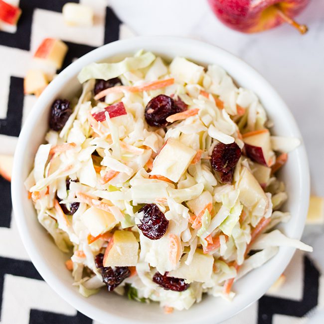 Cranberry Apple Coleslaw in a small white bowl sitting on a black and white chevron napkin