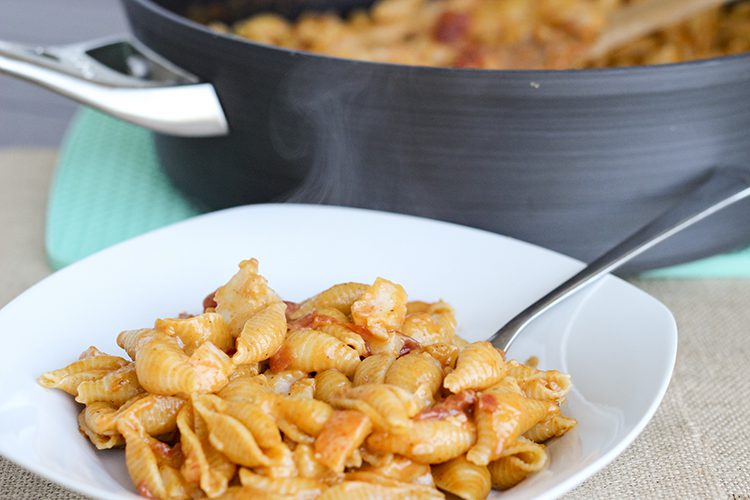 Close up of a bowl of lobster mac and cheese in front of the stockpot