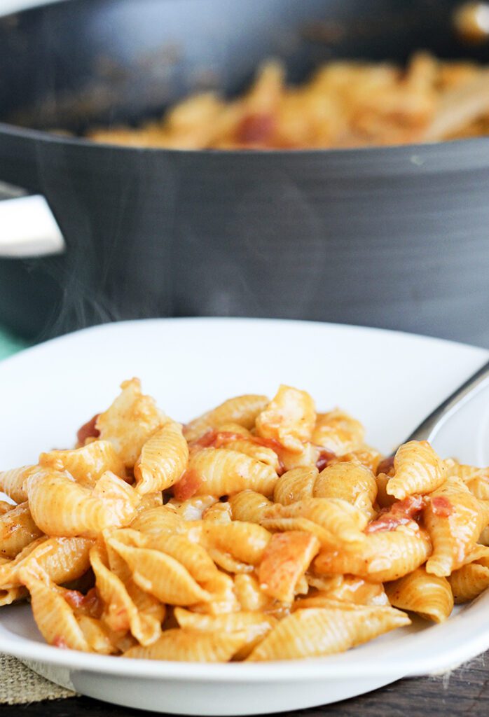 Steaming bowl of lobster mac and cheese in front of black stockpot