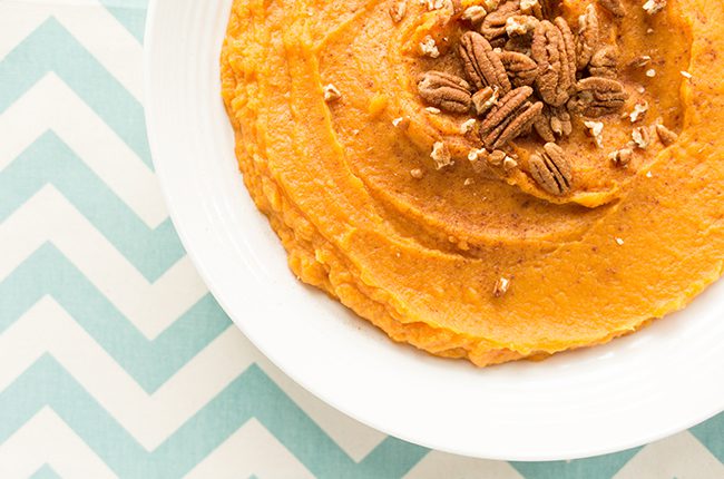 Overhead picture of white bowl on blue cloth filled with mashed sweet potatoes
