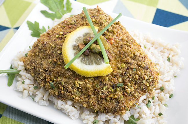 Pistachio baked halibut recipe on a white plate on a blue and green cloth