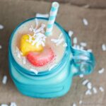 Pineapple and strawberry on top of smoothie in blue jar