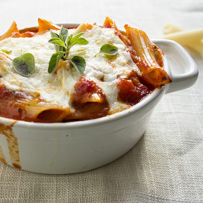 Close up picture of lasagna casserole in small white bowl sitting on a tan napkin