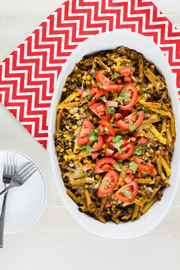 An overhead picture of tex mex pasta casserole sitting on a red and white chevron cloth