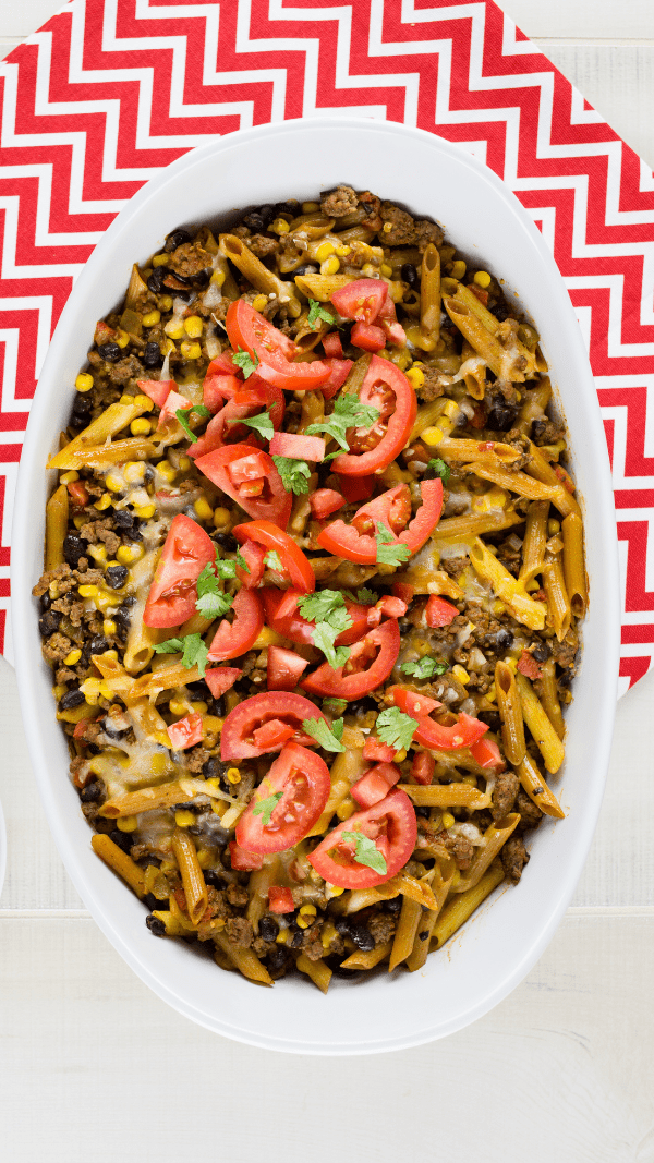 An overhead picture of tex mex pasta casserole sitting on a red and white chevron cloth