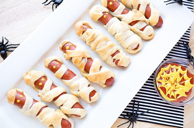 Baked mummy hot dogs for halloween on white platter
