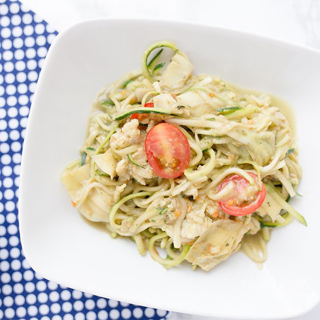A single white bowl filled with creamy avocado pasta with zoodles
