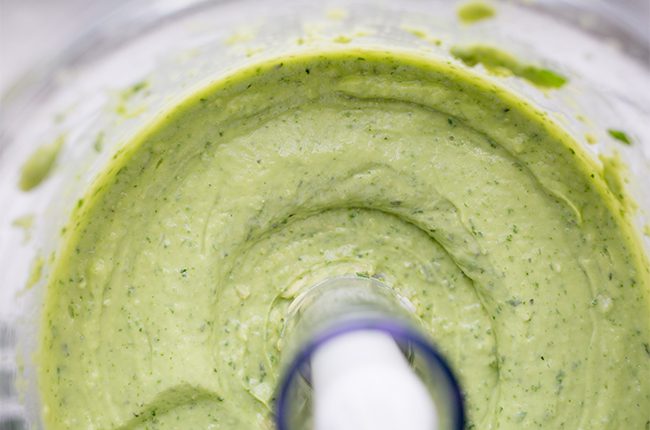 Avocado sauce in a food processor being blended