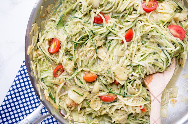 Skillet filled with zoodles tomatoes and avocado cream sauce for pasta