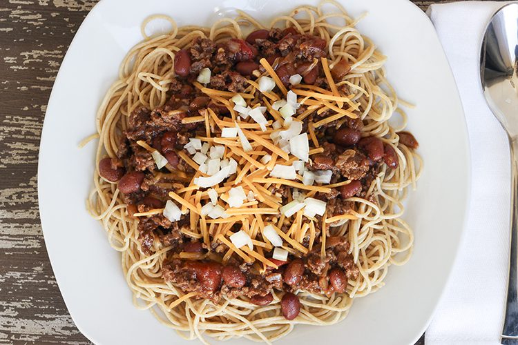 Cincinnati chili recipe sitting on a white plate over spaghetti noodles