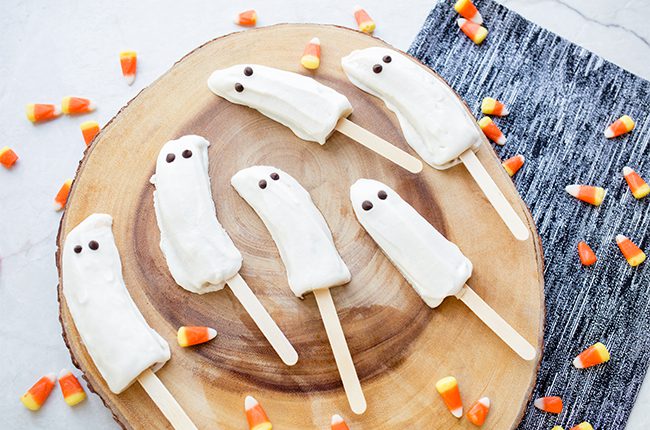 Frozen banana ghosts on wooden plate ready to be eaten