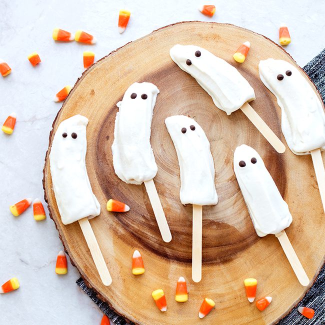 Frozen banana ghosts sitting on wooden surface