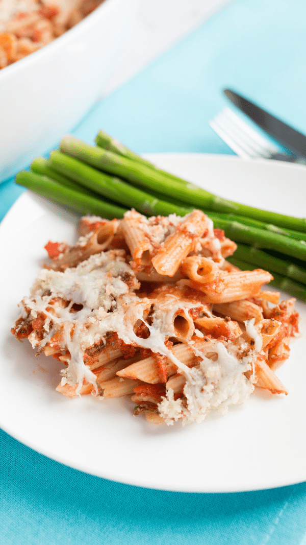 chicken parmesan casserole on a white plate with asparagus