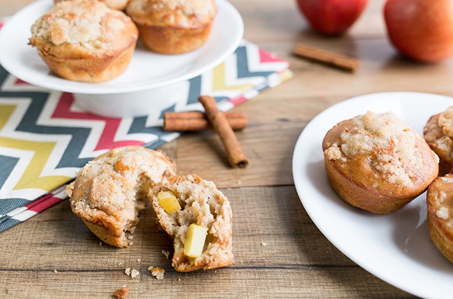 Apple cinnamon muffins sitting on wooden table ready to be eaten