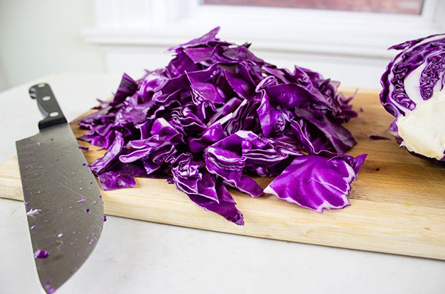 Cabbage being sliced on a cutting board