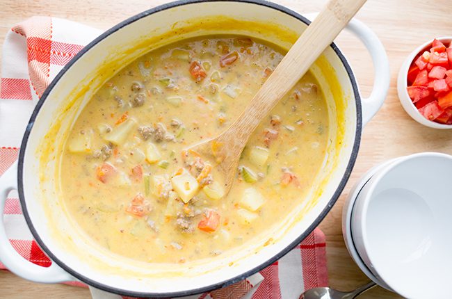 Overhead picture of stirring cheeseburger soup in large stockpot