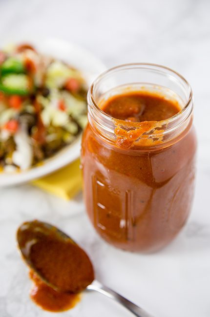 Enchilada sauce in a glass mason jar in front of ingredients